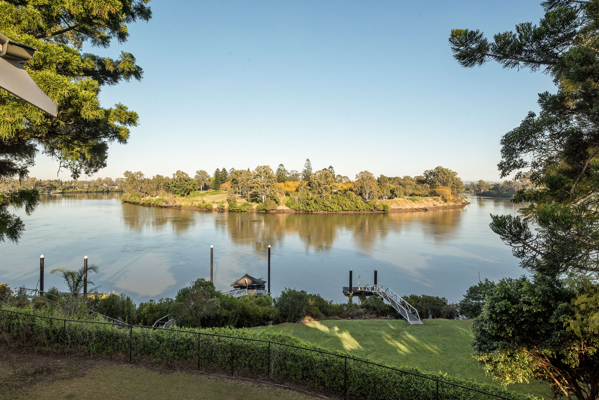 Panoramic Brisbane River outlook across the waterfront lawn and private pontoon