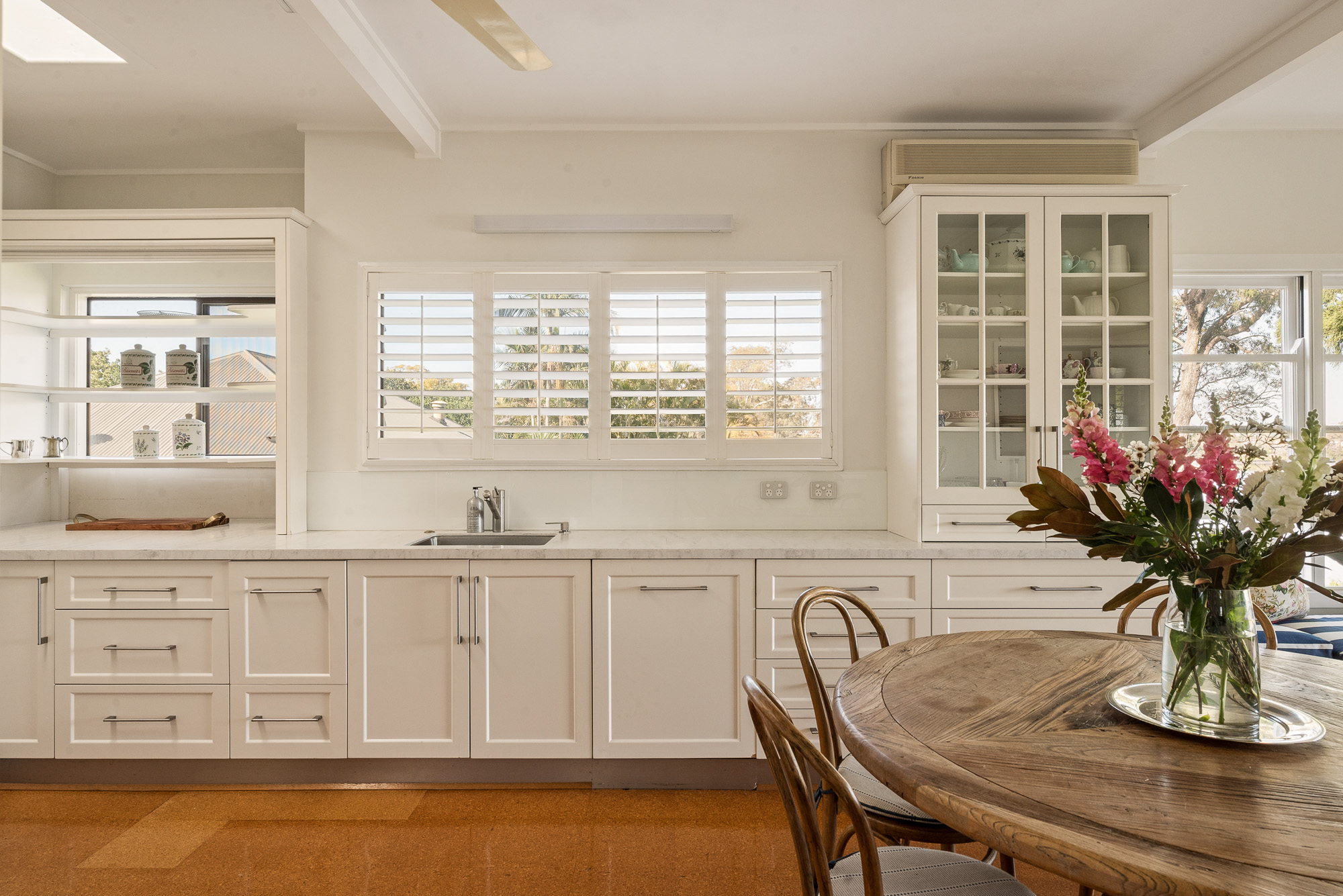 White kitchen with stone benchtops and plantation shutters